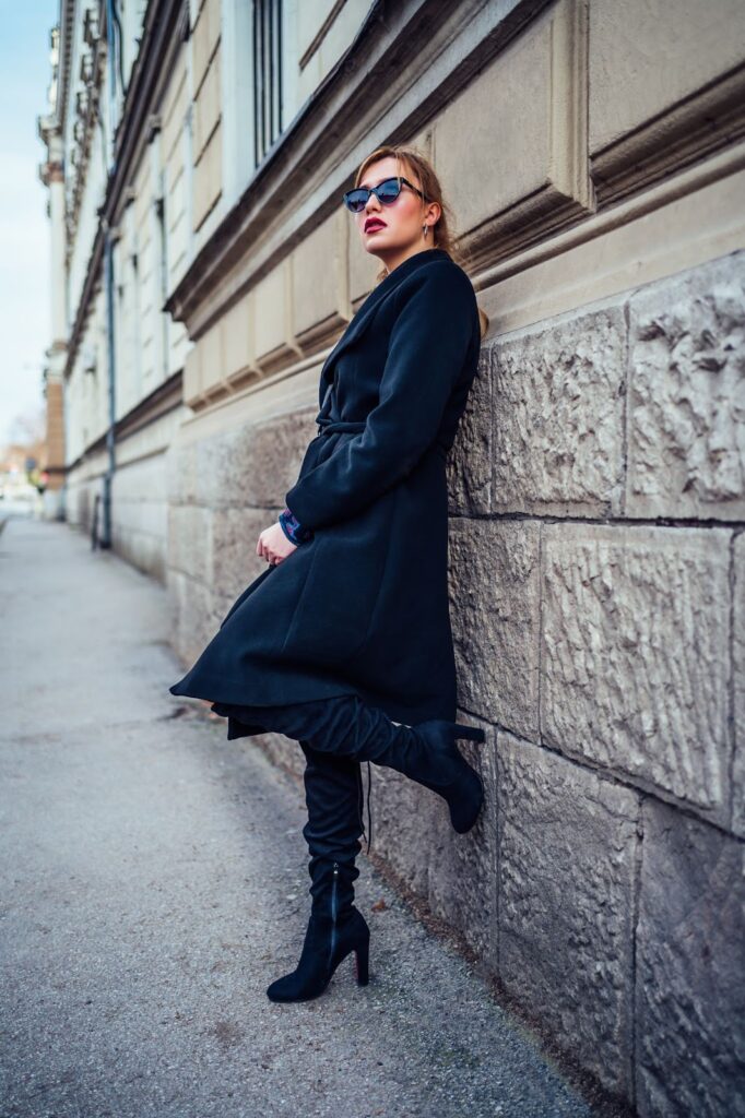 Moteris, dėvinti juodą paltą ir avinti juodus ilgaaulius