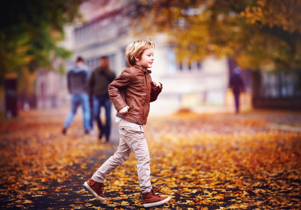 Vaikas rudeninių lapų fone