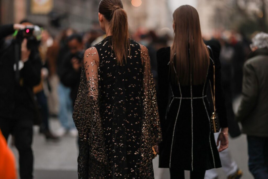 Dvi merginos, vilkinčios puošnias juodas sukneles