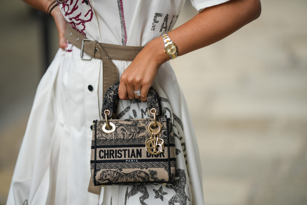 Moteris, laikanti proginę Christian Dior rankinę
