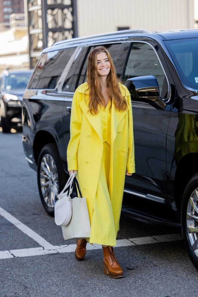 Moteris, dėvinti ryškiai geltonus drabužius ir rudus aulinukus