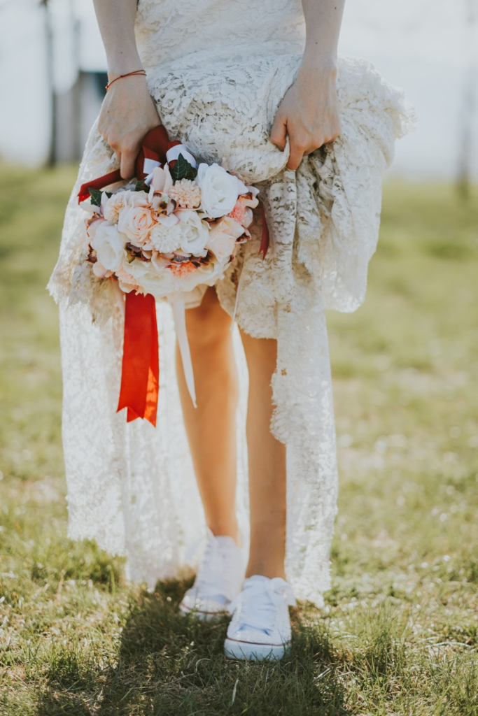 Moteris, devinti boho stiliaus vestuvinę suknelę ir baltus sportbačius